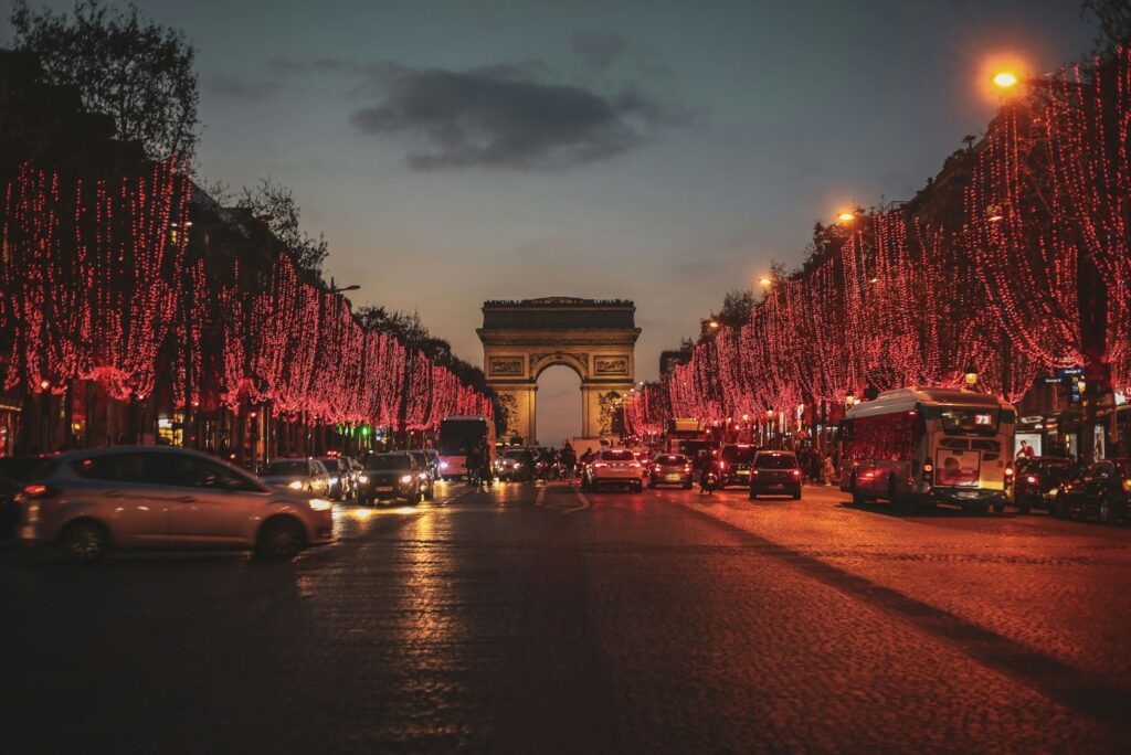 The Champs-Élysées lit with red lights leading to the Arc de Triomphe