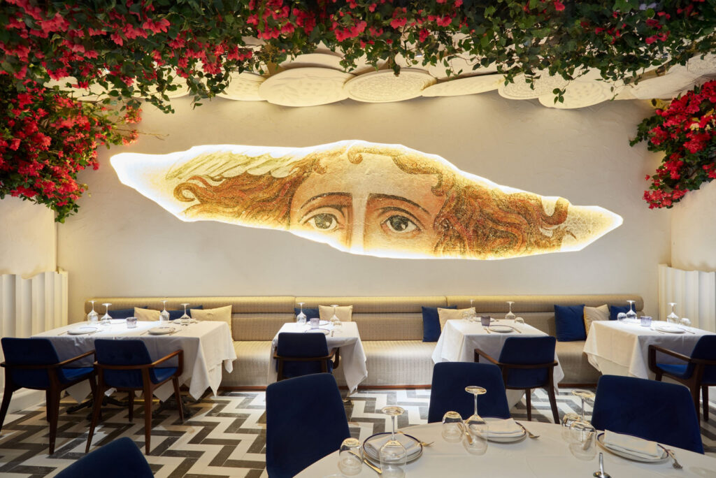 Banquette seating beneath a lit mosaic wall at OPA Dubai restaurant