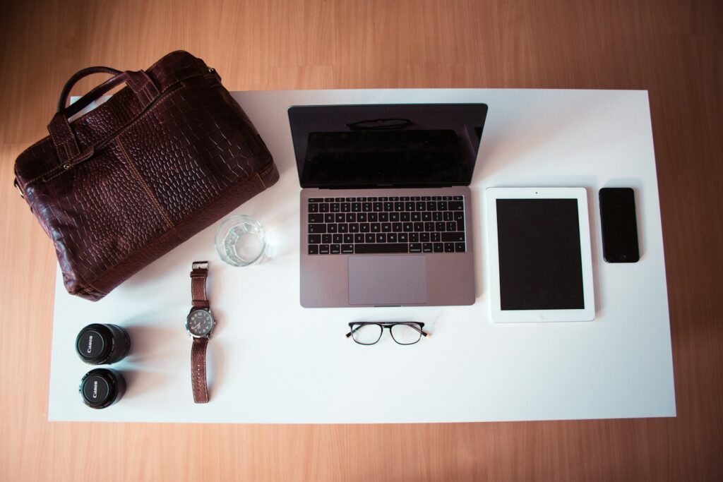A leather briefcase, laptop, and everyday essentials laid out on a desk