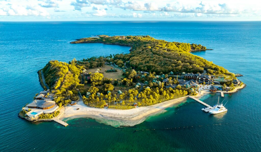 Private island rental — a small forested island in turquoise water seen from above