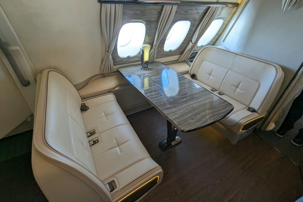 Private jet cabin with cream leather sofas and a table beside the windows