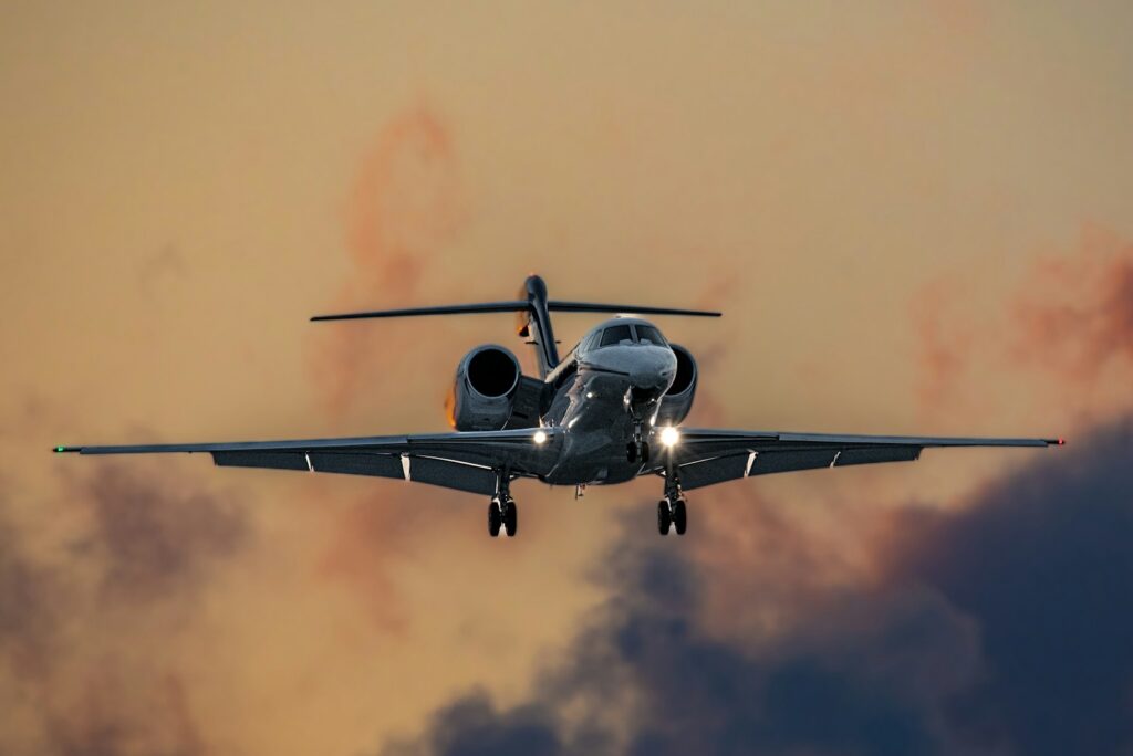 Private jet flying through a pink evening sky
