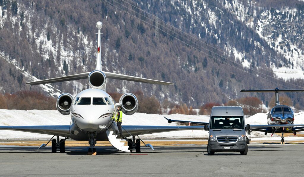 Private jet concierge services — a business jet in a hangar with a car waiting alongside