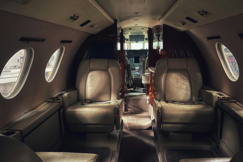 Private jet cabin with leather armchairs facing each other along a narrow aisle