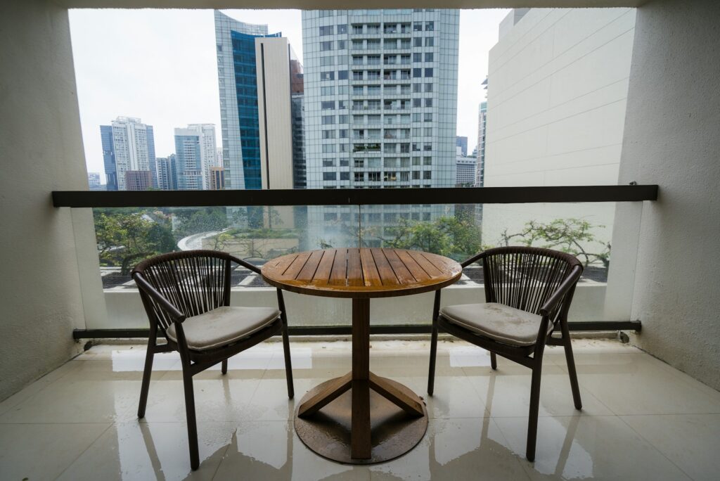 A balcony with two chairs and a round table overlooking a city skyline