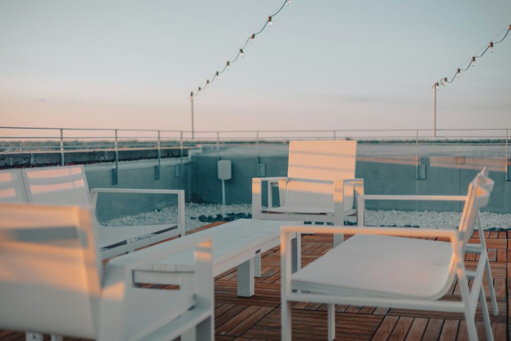 A quiet roof terrace at dusk with white lounge furniture and string lights