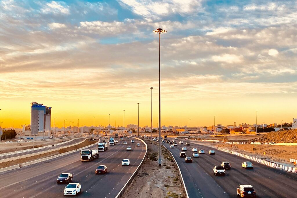 Multi-lane highway in Jeddah at sunset under a sky of soft orange clouds.