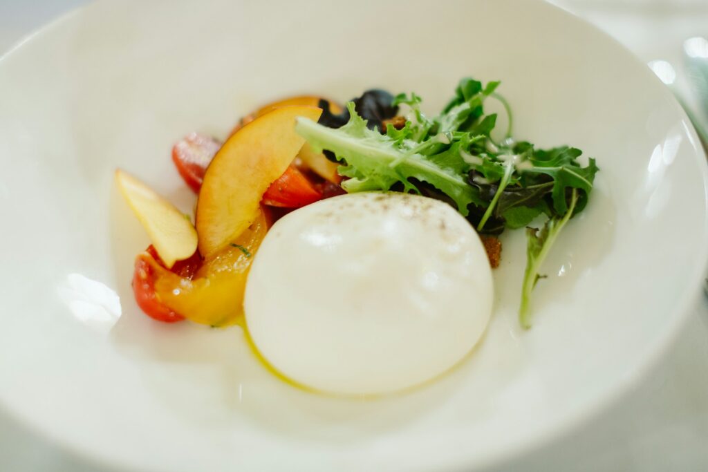Burrata starter with tomatoes and olives on a white plate