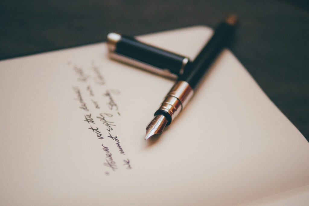 A fountain pen resting on a handwritten letter on a desk