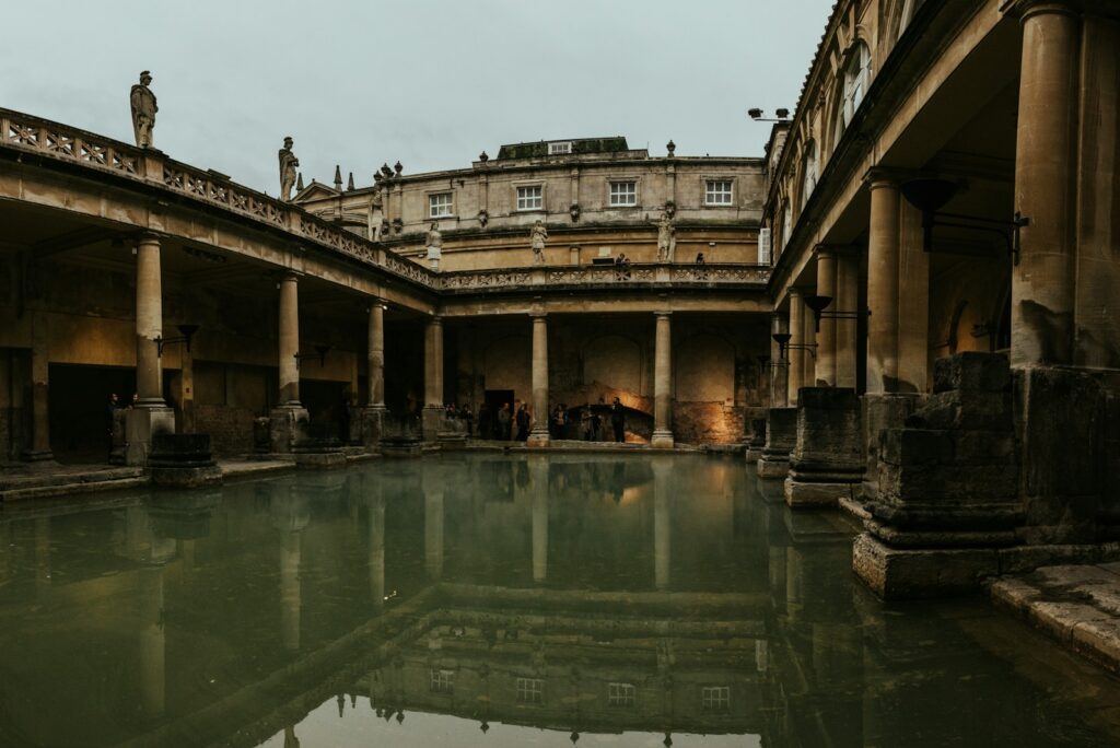 Still green water and stone colonnades of the Roman Baths in Bath, England