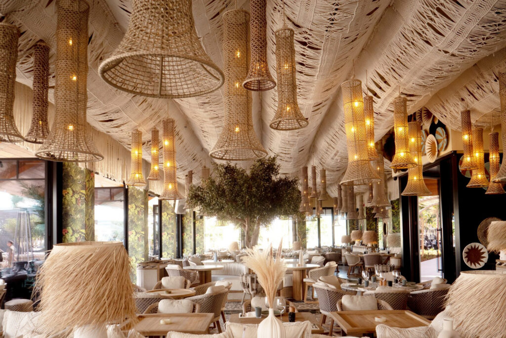 Restaurant interior at Verde Beach with woven lanterns and a central olive tree