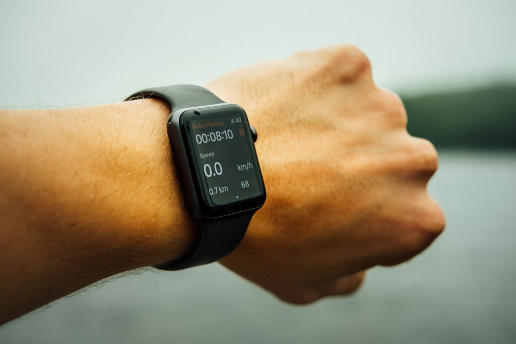 Wrist-worn fitness watch showing workout time and heart rate beside a calm lake
