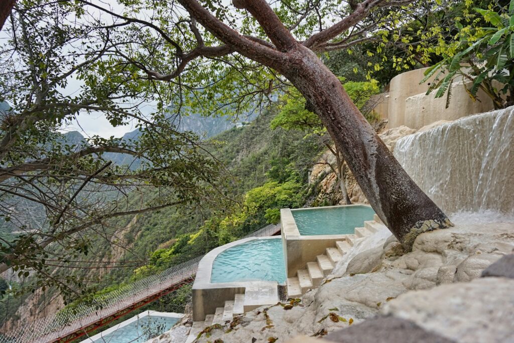 Terraced spa pools beside a waterfall in a green mountain valley