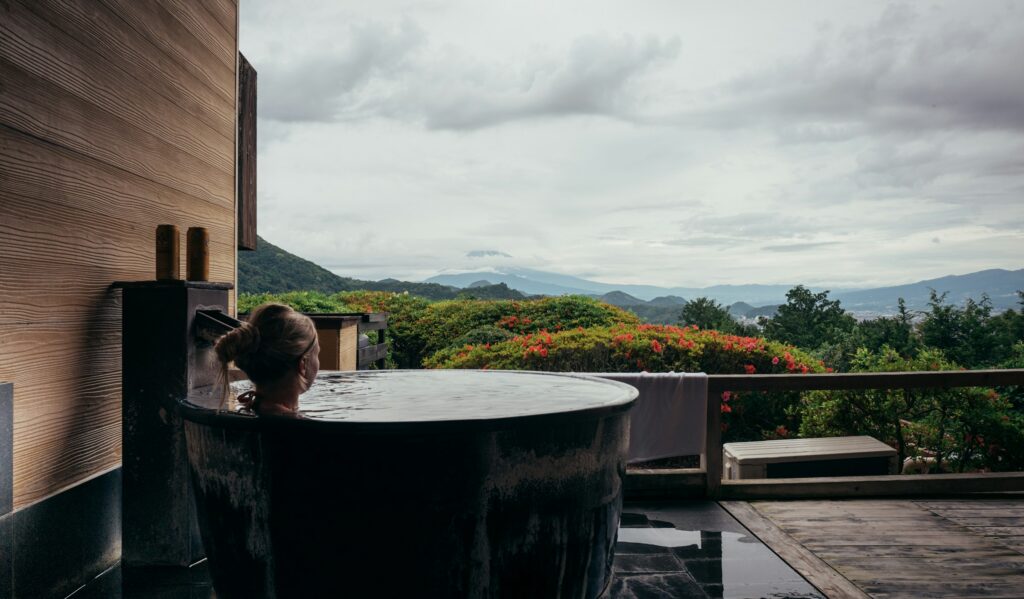Women's wellness retreat: a guest relaxing in a private terrace bath overlooking gardens and hills
