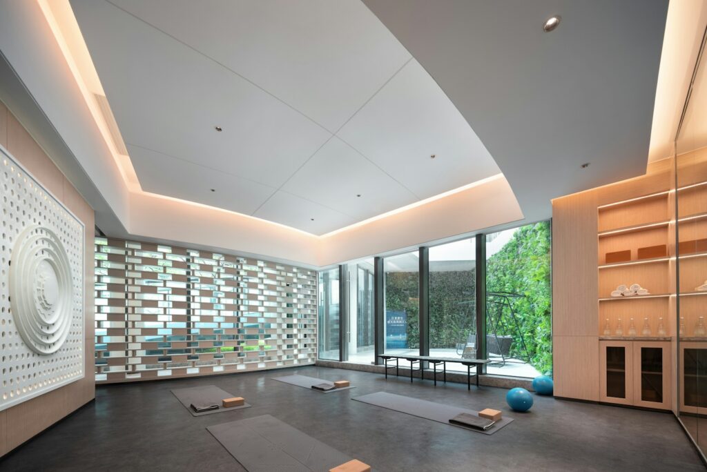Quiet yoga studio with mats, blocks, and a wall of glass opening onto greenery