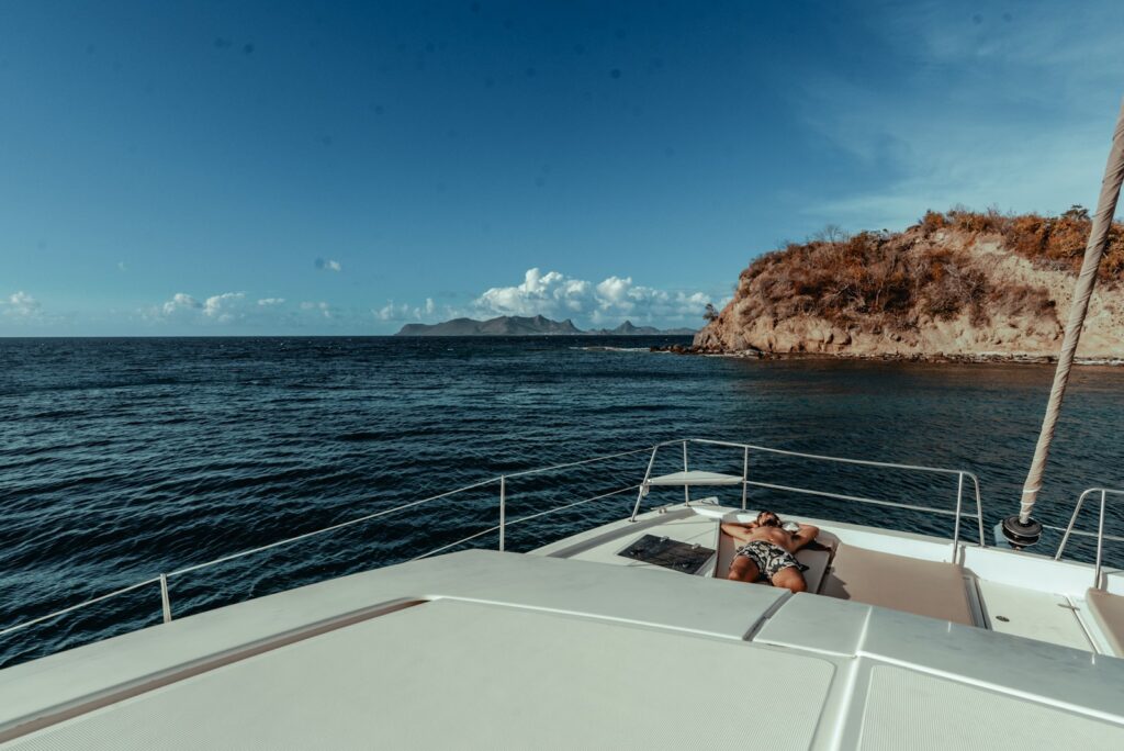 View from a yacht bow across deep blue water towards a rocky island in the Grenadines