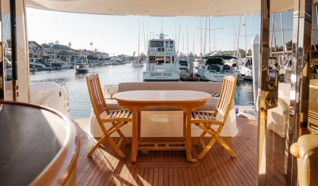 Teak aft deck with a dining table on a charter yacht moored in a marina, illustrating yacht charter cost