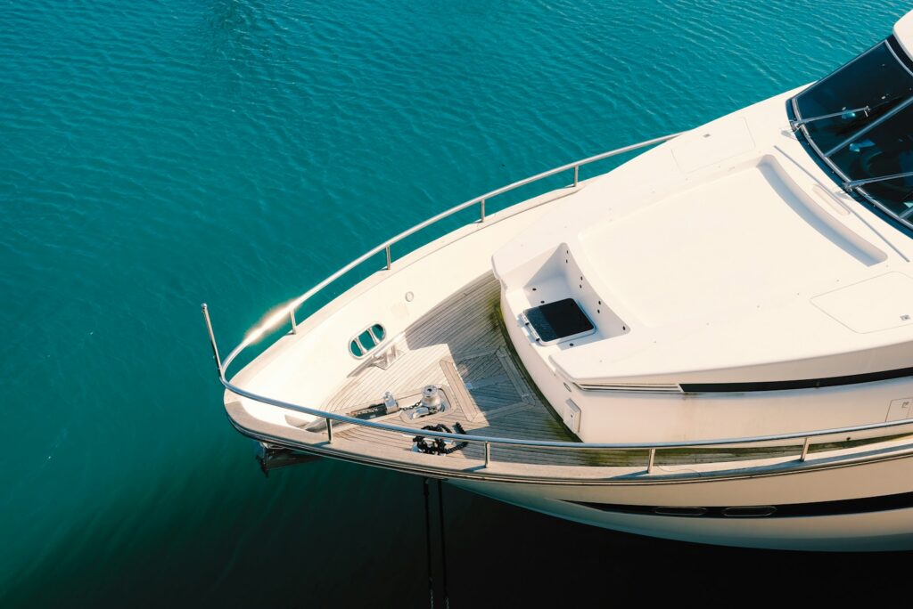 White and blue motor yacht seen from above on calm green water