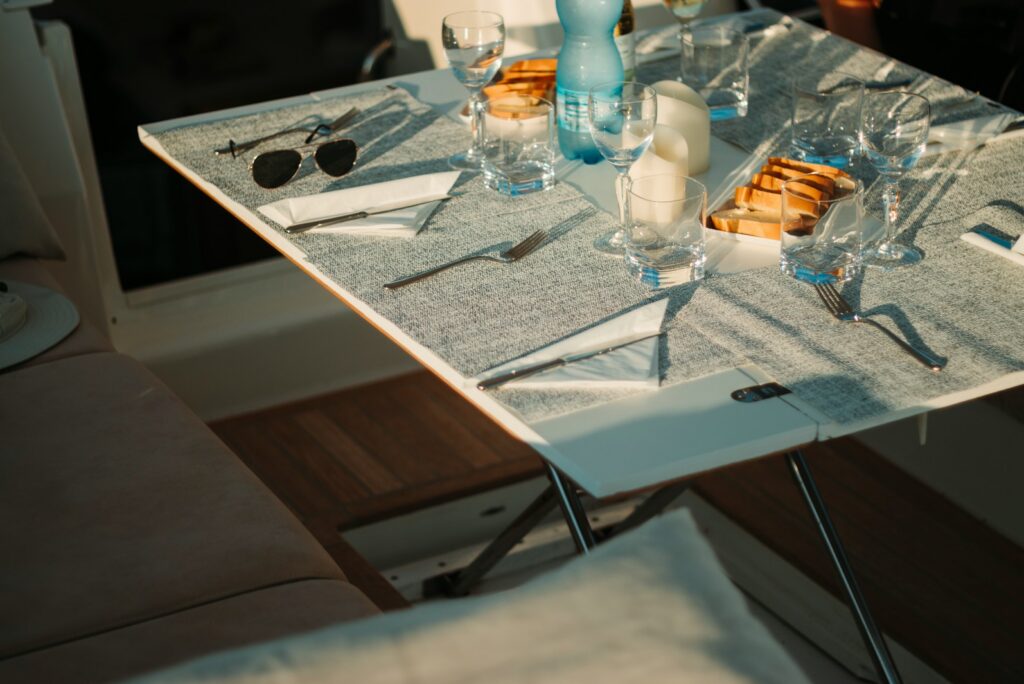 Table laid with glassware and cutlery on the deck of a yacht.
