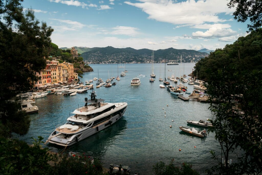 Superyacht moored in a sheltered Italian bay beside a harbour of pastel-coloured houses.