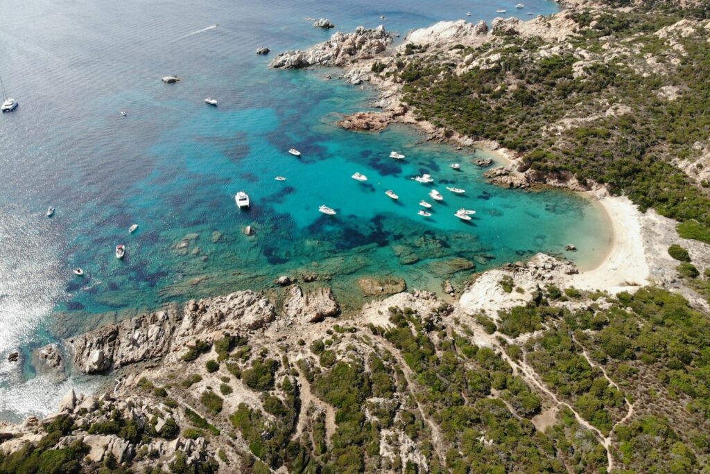 Aerial view of boats anchored in a turquoise cove on the Sardinian coast