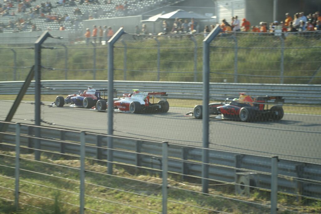 Single-seater race cars passing a trackside fence at Circuit Zandvoort