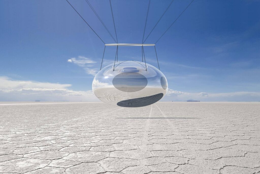 A transparent passenger capsule hanging beneath balloon lines above a white salt desert