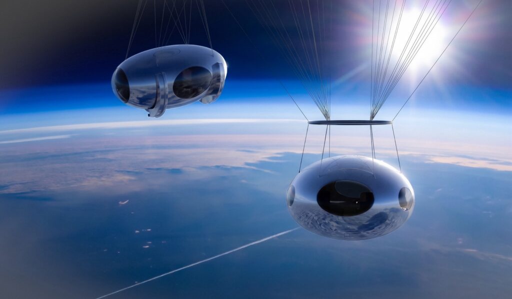 Two Zephalto capsules suspended beneath their balloons above the curvature of the Earth