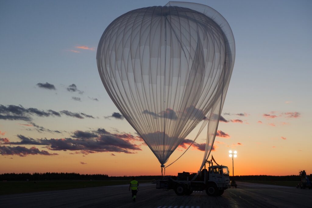 A stratospheric balloon inflated on a launch field at sunset